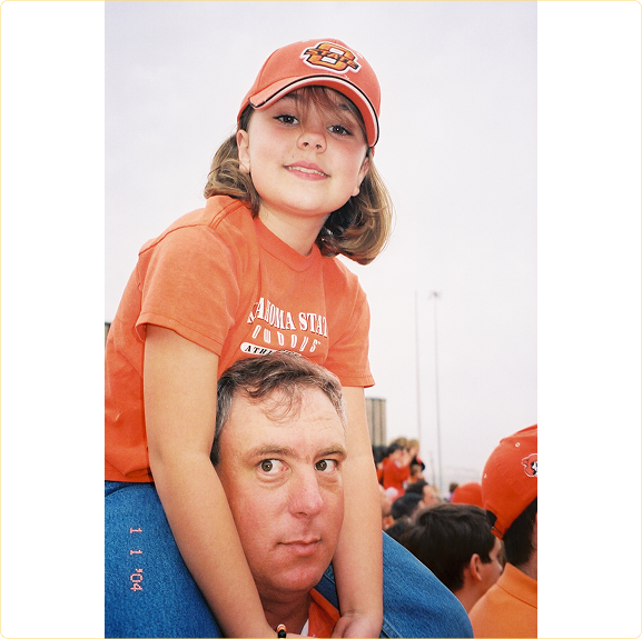 Brittany on her dad's shoulders at an Oklahoma State football game, several years before his cancer battle